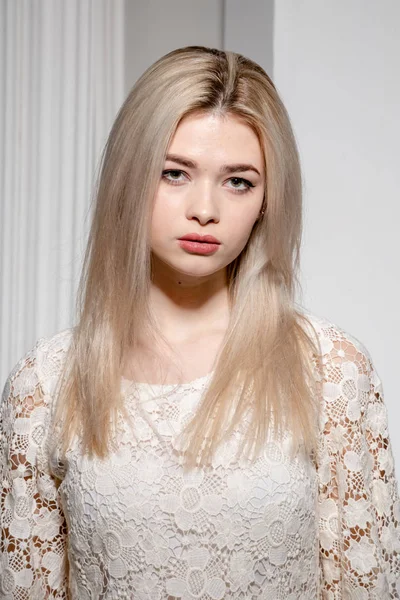 Een blond meisje in een witte jurk poseert in een witte foto Studio — Stockfoto