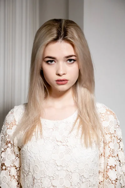 Uma menina loira em um vestido branco posa em uma foto branca Studio — Fotografia de Stock