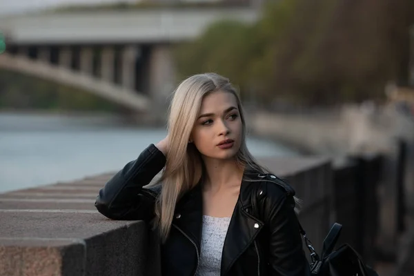 年轻的金发女人穿着皮夹克，手提包在城市街道上 — 图库照片