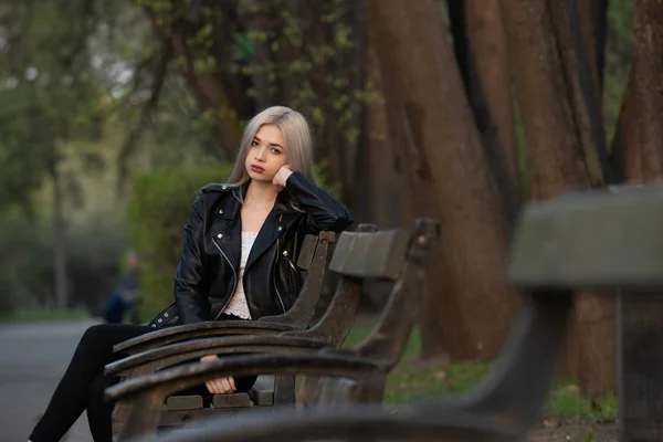 Bela jovem loira menina sentado em um banco de parque — Fotografia de Stock