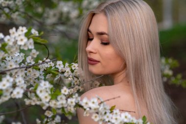 Bahar kiraz bahçesinde güzel sarışın kız