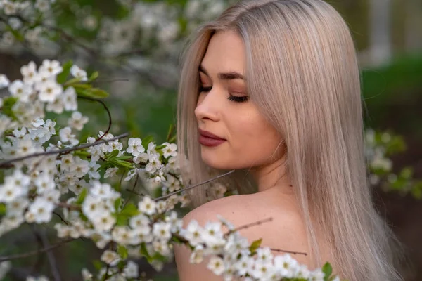 Bahar kiraz bahçesinde güzel sarışın kız