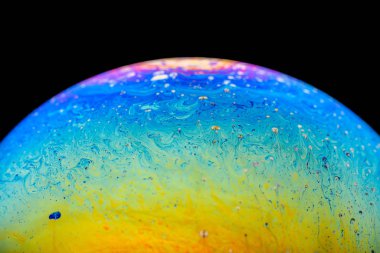 İzole edilmiş siyah bir arka planda gökkuşağı sabun köpüğü. Renkli yüzeye yakın çekim. Poster boş