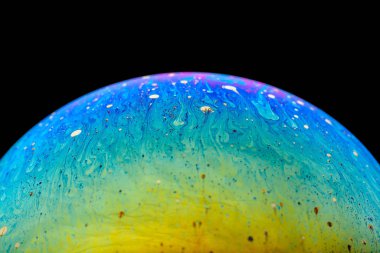 İzole edilmiş siyah bir arka planda gökkuşağı sabun köpüğü. Renkli yüzeye yakın çekim. Poster boş