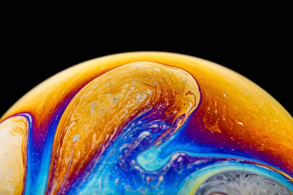 Rainbow soap bubble on an isolated black background. Close-up of the colorful surface. Poster blank — Stock Photo, Image