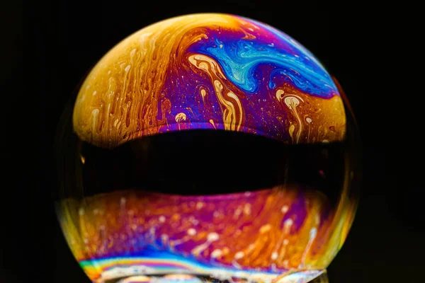 Rainbow soap bubble on an isolated black background. Close-up of the colorful surface. Poster blank — Stock Photo, Image