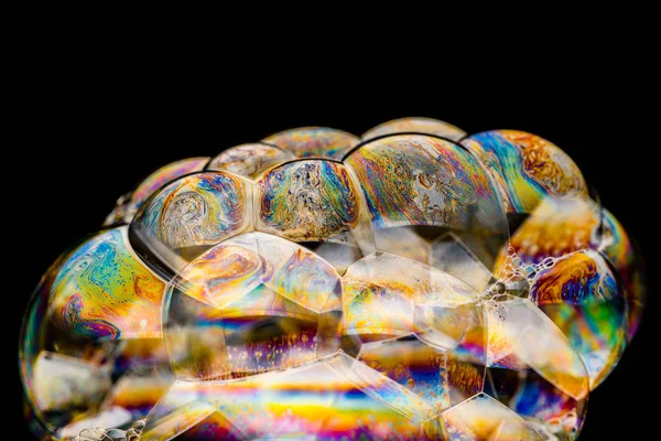 Rainbow soap bubble on an isolated black background. Close-up of the colorful surface. Poster blank — 스톡 사진