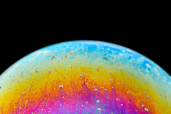 Duhová mýdlová bublina na izolovaném černém pozadí. Detailní záběr barevného povrchu. Prázdný plakát — Stock fotografie