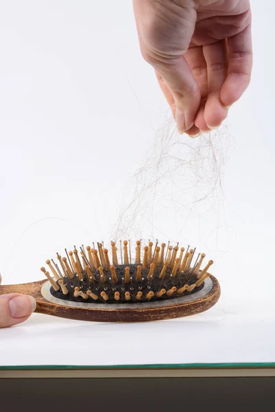 Health problems that cause hair loss and hair loss. Women's wooden brush with the rest of the hair on a light surface — Stock Photo, Image