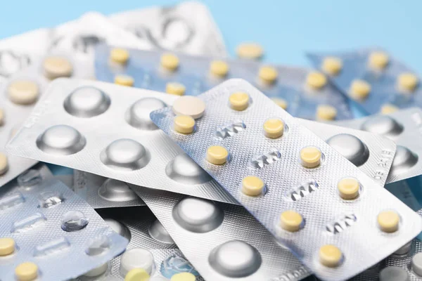 Witte blisterverpakking met tabletten pilstatines voor lichtbestendige verpakkingen op blauwe achtergrond. Witte en gele tabletten — Stockfoto