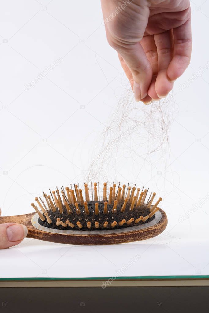 Health problems that cause hair loss and hair loss. Women's wooden brush with the rest of the hair on a light surface