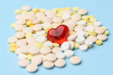 Mavi arka planda sarı ve beyaz haplar. Merkezde kırmızı bir kalp ile yakın plan.