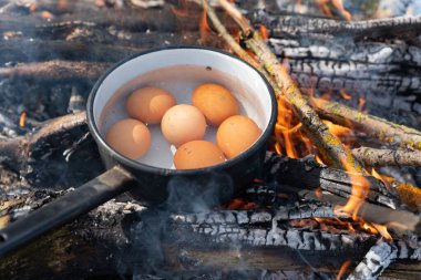 Kamp ateşinde kaynamış su dolu bir kazanda yumurtalar