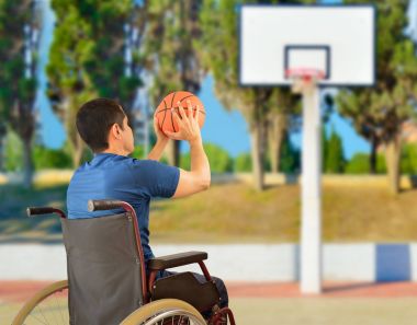 Tekerlekli sandalyedeki adam basketbol oynuyor.