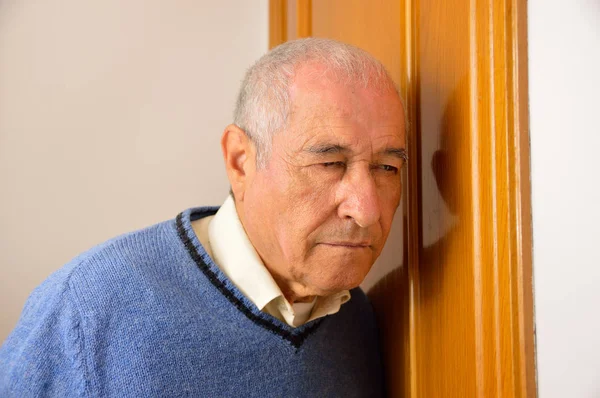 年配の男性がドアの後ろに耳を傾け — ストック写真