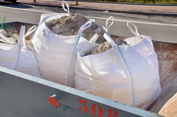 Контейнер зі сміттєвими пакетами, наповненими залишками бетону — стокове фото