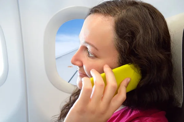 Vrouw met behulp van smartphone in het vliegtuig — Stockfoto