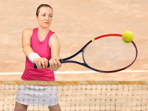 Frau schlägt den Ball im Tennis — Stockfoto