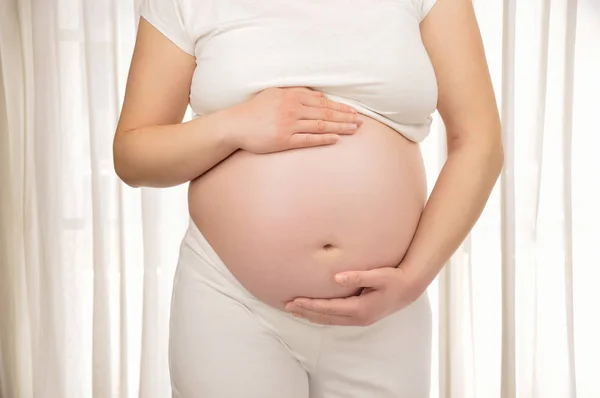 Женщина держит ее беременный живот — стоковое фото