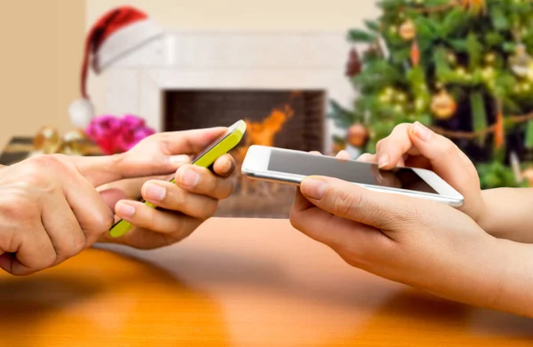 Två personer med smartphones ansluta på xmas — Stockfoto