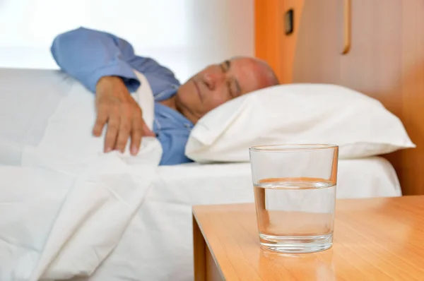 Senior man sleeping with water — Stock Photo, Image