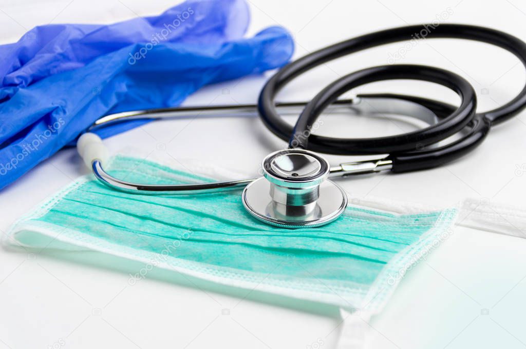 Shot of a stethoscope ,glove and mask lying on top of a white table