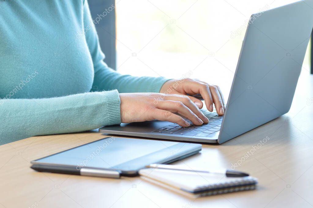 Cropped shot of a woman hands typing on a laptop keyboard on a desk at office