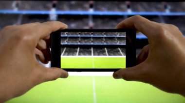 Stadyumda video çekip futbol maçı izleyen bir adam.