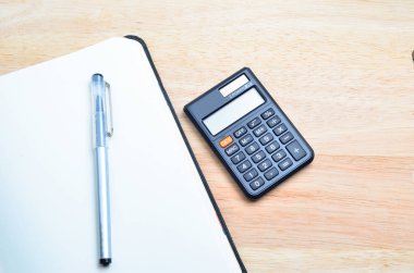 Defter ve kalem ile ahşap masa hesap makinesi