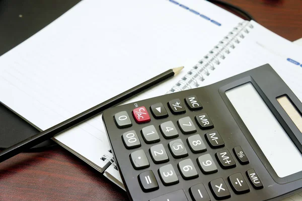 Calculadora e caneta em notebook em branco . — Fotografia de Stock