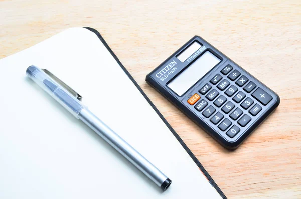 Caderno e caneta com calculadora na mesa de madeira — Fotografia de Stock