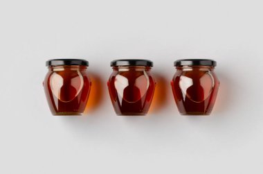 Gri bir arka planda üç bal kavanozu..