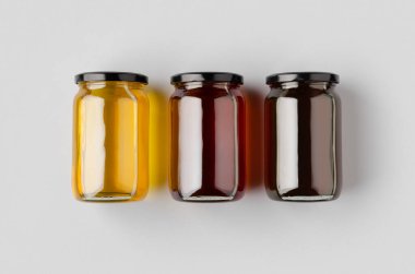 Gri bir arka planda üç bal kavanozu..