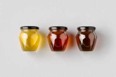 Gri arka planda bal kavanozları modeli. Üç farklı renk..