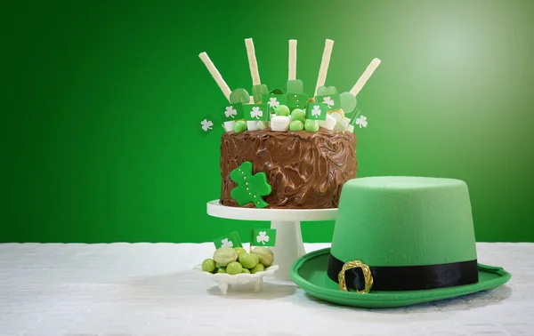 Mesa de fiesta de San Patricio con pastel de chocolate, sombrero de duende y lente llamarada . —  Fotos de Stock