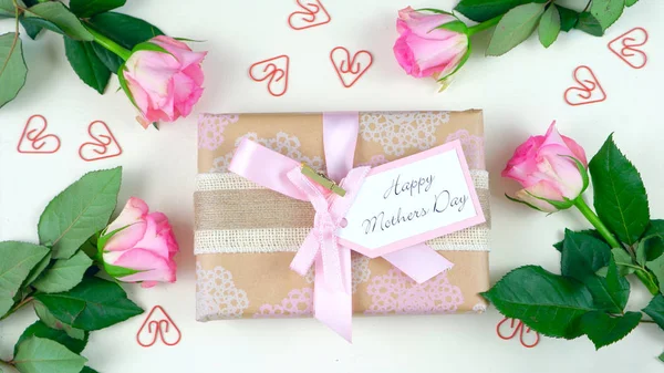 Día de las Madres arriba con regalo y rosas rosadas sobre fondo de mesa de madera blanca —  Fotos de Stock