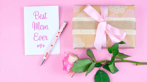 Dia das Mães sobrecarga com rosas, melhor mãe já cartão e presente na mesa rosa . — Fotografia de Stock