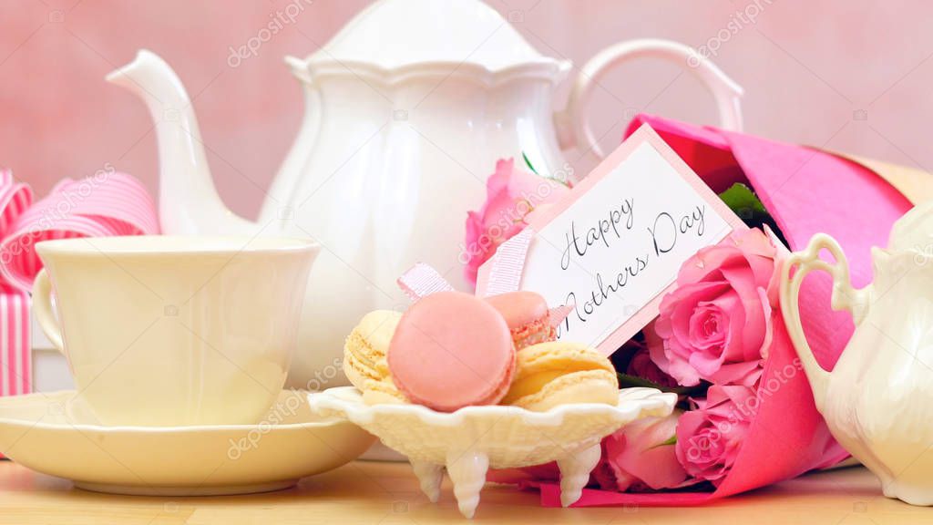 Mothers Day tea setting with macaron cookies, pink roses and gift, closeup.