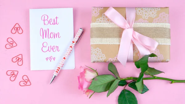 Día de las Madres sobrecarga con rosa, tarjeta Best Mom Ever y regalo en mesa rosa . — Foto de Stock