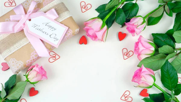 Ημέρα της μητέρας επιβάρυνση με είδη δώρων και ροζ τριαντάφυλλα σε φόντο λευκό τραπέζι από ξύλο — Φωτογραφία Αρχείου