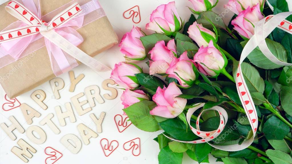 Mothers Day overhead with gift and pink roses on white wood table background