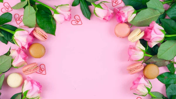 Dia das Mães fundo de rosas rosa e biscoitos macaron na mesa de madeira rosa . — Fotografia de Stock