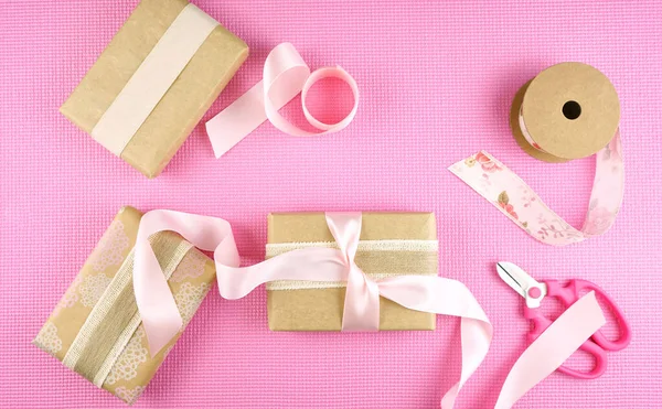 Ajándékok csomagolva Kraft papír és rózsaszín szalagok felső flatlay. — Stock Fotó