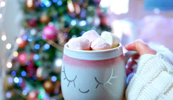 Mujer sosteniendo chocolate caliente frente al árbol de Navidad . — Foto de Stock