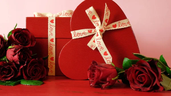 Cadeaux Saint-Valentin et roses rouges sur fond de table en bois rouge . — Photo