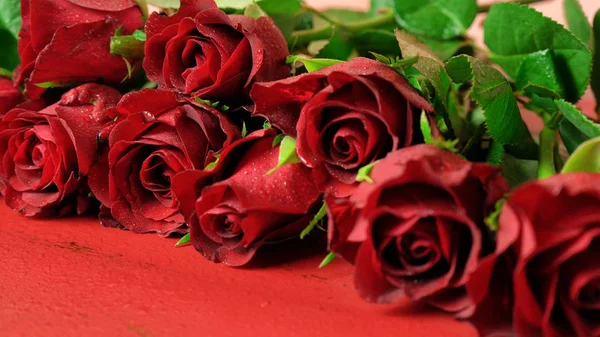 Walentynki prezent z czerwonych róż makro zbliżenie na czerwonym tle drewna. — Zdjęcie stockowe