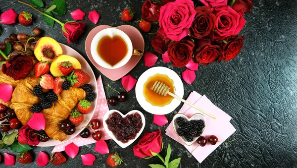 Romantická shovívavá snídaně s croissanty, palačinkami, vaflemi s ovocem a růžemi. — Stock fotografie