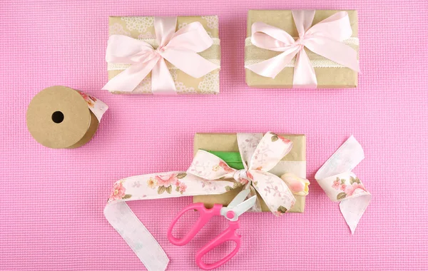 Geschenken verpakt in Kraft papier en roze linten overhead flatlay. — Stockfoto