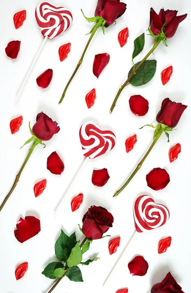 Red roses, petals, lollipops and chocolates creative composition layout. — Zdjęcie stockowe