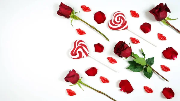 Red roses, petals, lollipops and chocolates creative composition layout. — Stockfoto